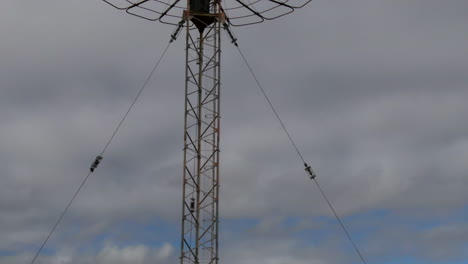 Drone-rises-above-huge-tall-communications-tower-in-Perth,-Western-Australia