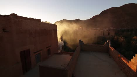 Kasbah-Unterkünfte-Im-Marokkanischen-Stil-Der-Todra-Schlucht-In-Der-Wüste-Mit-Sich-Schnell-Bewegendem-Rauch-Auf-Dem-Dach,-Der-In-Die-Sonne-Aufsteigt