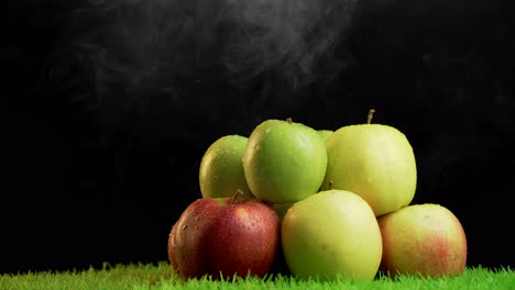 Haufen-Verschiedenfarbiger-Äpfel-Vor-Schwarzem-Hintergrund-Mit-Rauchdampf-Darüber