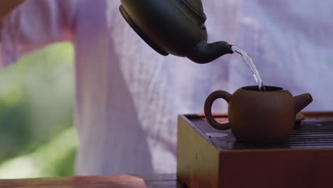 Man-pours-water-into-teapot,-steeps-tea,-relaxing-pleasure,-calming