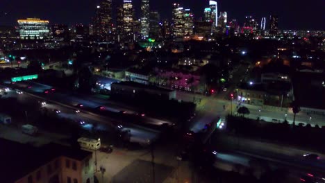 Luftaufnahmen-Neigen-Sich-Vom-Verkehr-Auf-Der-Autobahn-Nach-Oben,-Um-Die-Skyline-Der-Innenstadt-Von-Los-Angeles-Bei-Nacht-Freizugeben