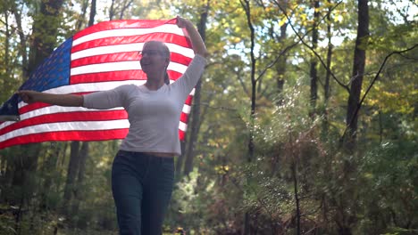 Backlit,-pretty-blonde-woman-walking-through-a-forest-holding-a-flag-up-in-the-air-behind-her
