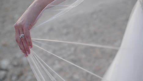 Close-up-slow-motion-shot-of-a-bride's-hand-with-wedding-ring-showing-as-she-holds-out-her-vile-as-it-gently-blows-in-the-wind