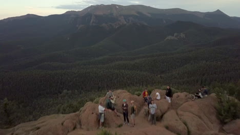 A-Group-of-Hikers-Enjoying-an-Amazing-Mountain-Top-View-in-the-Colorado-Rocky-Mountains,-Aerial-Flyby-Tilt-Up-to-Reveal-a-Mountian-Peak-in-the-Distance
