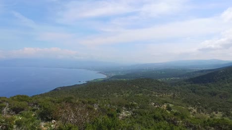 Drone-shot-rises-from-the-trees-high-in-the-air-revealing-the-beautiful-green-land-and-blue-sea-of-Akamas-Cyprus