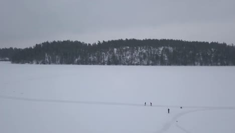 Wide-aerial-shot-of-four-nature-lovers-enjoying-the-cold-and-crisp-temperatures-during-a-morning-stroll-on-vast-frozen-lake