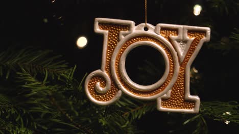 A-hand-painted-Christmas-ornament-saying-"Joy"-hanging-on-a-Christmas-Tree