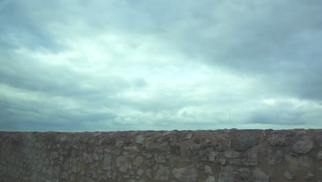 Moving-along-a-stone-wall-with-a-cloudy-sky