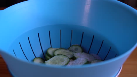 Putting-salt-on-cucumber-slices-and-tossing-them-up-in-a-strainer
