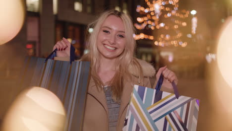 Young-attractive-lady-holds-up-shopping-bags-and-smiles-to-camera