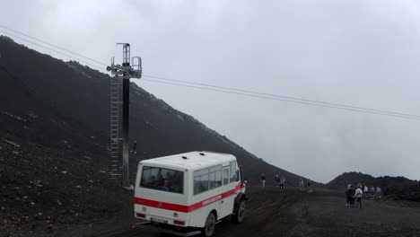 Gente-Caminando-Hacia-El-Cráter-Del-Monte-Etna-Con-Una-Minivan-Blanca-Pasando