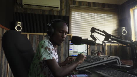 Radio-announcer-from-a-local-Ugandan-radio-station-reading-news-and-checking-smartphone,-Uganda-Africa