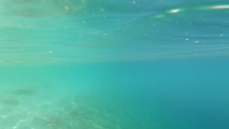 Tauchen-Sie-Aus-Dem-Wunderschönen-Türkisfarbenen-Wasser-Mit-Reflexionen-Und-Licht-Auf-Der-Oberfläche-Und-Dem-Strand-In-Der-Ferne