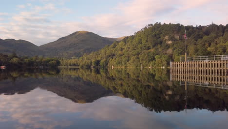 Mirror-reflection-on-a-calm-Ullswater-lake-of-hills,-woods-and-sky