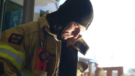 Firefighter-puts-on-protective-firefighting-coat-and-gear-as-he-prepares-to-respond-to-an-emergency