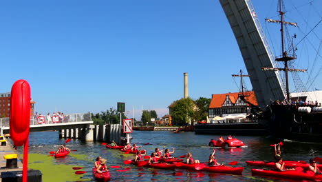 the-crowd-of-tourist-in-the-red-colored-kayaks-paddling-under-the-Drawbridge-and-the-pirate-boat-sailing-in-the-opposite-direction