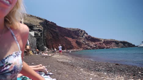 Wide-Shot-of-Red-Beach-Turns-into-a-Close-Up-of-a-Woman-Who-Looks-at-Her-Phone-Instead-of-The-Beautiful-Surroundings-of-Red-Beach-in-Akrotiri-Santorini-Greece