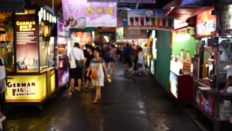 Essensstände-Auf-Dem-Nachtmarkt-Und-Junge-Taiwanesische-Kunden,-Die-Nachts-Nach-Einem-Regenschauer-Vorbeilaufen