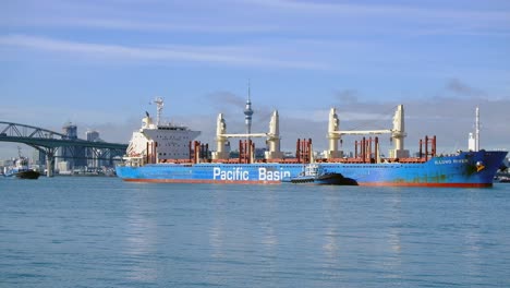 Nahaufnahme-Eines-Frachtschiffs,-Das-Zur-Chelsea-Zuckerfabrik-Im-Hafen-Von-Auckland-Fährt,-Mit-Sky-City-Und-Harbour-Bridge-Als-Hintergrund