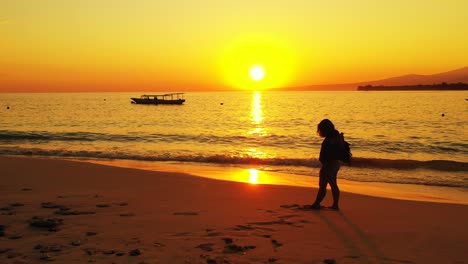 Attraktive-Junge-Frau-Am-Strand-Mit-Schwenkendem-Schal-An-Einem-Windigen-Sommerabend-Bei-Wunderschönem-Goldenen-Sonnenuntergang-Auf-Der-Verträumten-Insel-Bali