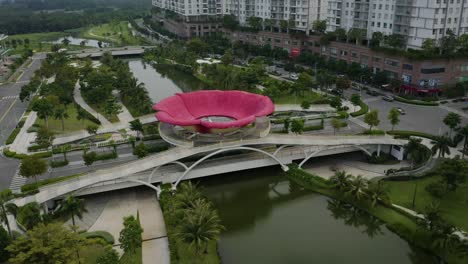 Aerial-view-flying-towards-a-contemporary-pedestrian-bridge-with-a-large-Sala-flower-on-top