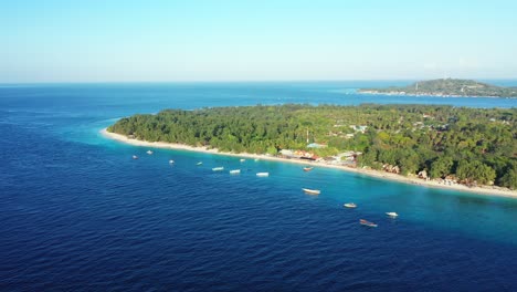 Capa-De-Isla-Tropical-Contorneada-Con-Una-Línea-Blanca-De-Playa-Exótica-Rodeada-De-Mar-Azul-Con-Barcos-Anclados-Cerca-De-La-Costa-En-Un-Día-Soleado-En-Indonesia
