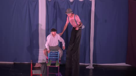 An-elderly-man-laughing-falls-during-a-comical-act-on-stage-for-children