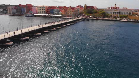 People-walking-over-Queen-Emma-Bridge-from-Otrabanda-to-The-Punda-neighbourhood-in-Willemstad,-Curacao