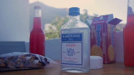 Weitwinkelaufnahme-Einer-Flasche-Griechischen-Ouzo-Und-Etwas-Digestif,-Nüssen-Und-Margaritas-Im-Hintergrund