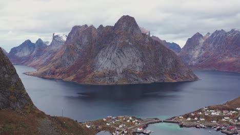 Steep-mountains-rise-up-from-the-sea-to-surround-small-flat-islands-with-fishing-villages-in-Lofoten,-Norway