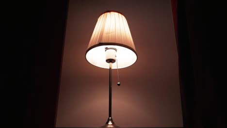 Close-up-shot-of-white-table-lamp-being-turned-on-with-a-male-hand