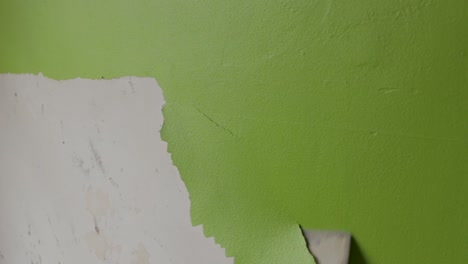 Ruhige-Aufnahme-Eines-Mannes,-Der-Grüne-Farbe-Von-Einer-Wand-Abkratzt