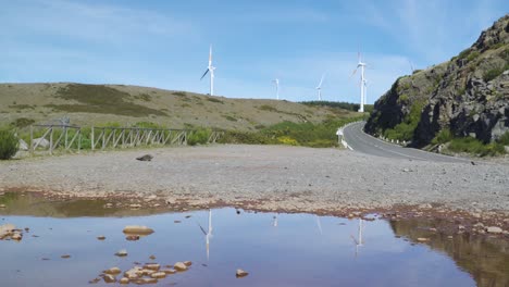 Aeolian-park-of-Paul-da-Serra,-some-Wind-turbines-turning-in-the-wind-reflected-in-a-small-poodle,-Ponta-do-sol,-Madeira-island,-Portugal