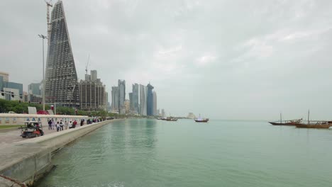 Zeitraffer-Der-Skyline-Von-Doha-Mit-Großen-Flaggen-Und-Traditionellen-Booten-Und-Tamin-Porträt-Auf-Booten