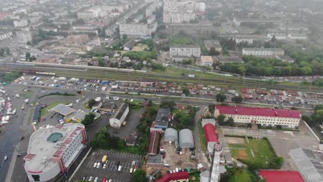 Aerial-View-of-Cityscape-Near-Railroad-Tracks-on-a-Foggy-Day-Tracking-Left