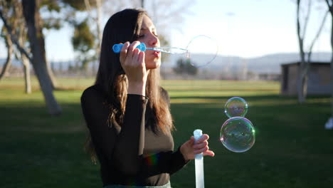 Happy-young-hispanic-woman-blowing-dreamy-bubbles-floating-in-the-bright-sunshine-outdoors-with-lens-flares-SLOW-MOTION