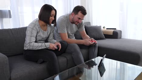 Friends-sit-on-a-couch-in-the-living-room-playing-very-focused-a-game-on-Nintendo-Switch