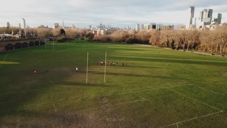 Aerial-drone-view-of-amateur-women-playing-american-football-or-rugby-in-the-park