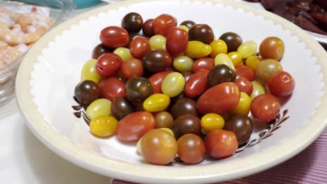 A-hand-grabs-a-cherry-tomato-from-a-bowl-of-mixed-cherry-tomatoes-in-4k
