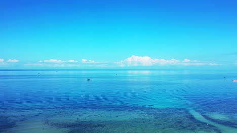 Beautiful-seascape-with-turquoise-shallow-lagoon-and-endless-ocean-reflecting-white-clouds-rising-on-bright-sky-in-Philippines