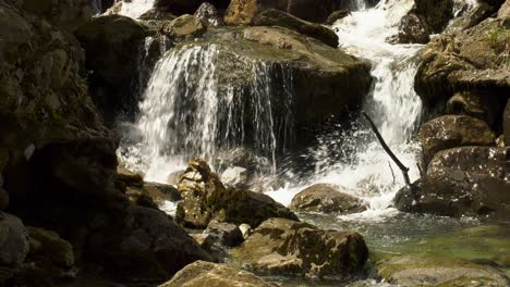 Mountain-stream-rushing-over-rocks-in-water,-slow-motion