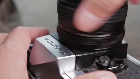 Caucasian-hands-screw-lens-onto-vintage-camera