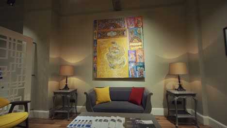 Large-yellow,-purple,-orange-painting-hanged-on-a-wall-inside-a-waiting-room-with-couch-and-a-coffee-table