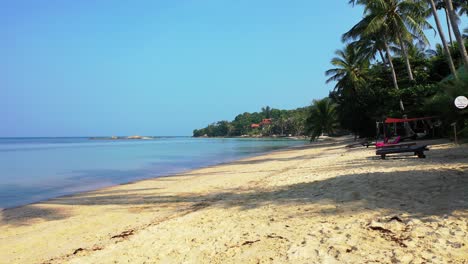 Exotischer-Strand-Mit-Sonnenliegen-Auf-Weißem-Sand-Unter-Palmen,-Umspült-Von-Ruhigem,-Klarem-Wasser-Der-Flachen-Lagune-In-Malaysia