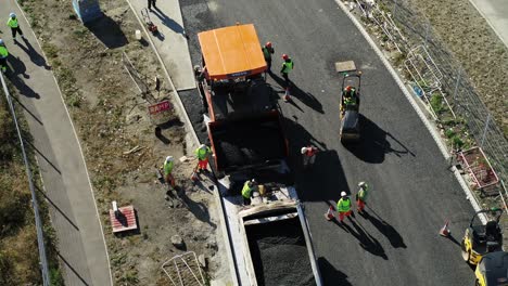 Aerial-view-of-a-road-surfacing-crew-laying-tarmac-on-a-new-road