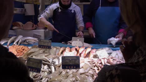 SLOWMO,-Fresh-fish-vendors-clean-fish-at-market-stand-while-customers-talk