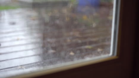 Rack-Focus-From-Wet-Window-to-Raindrops-Falling-on-Wooden-Deck