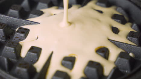 Up-close-macro-view-of-freshly-prepared-waffle-batter-filling-up-hot-waffle-maker-for-morning-breakfast