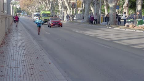 Sporty-People-Running-On-The-Street-With-Escort-Vehicles---Zurich-Marathon-2019-In-Malaga,-Spain---long-shot