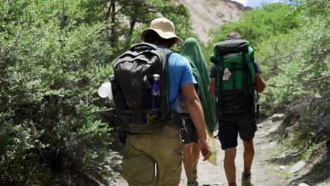 Close-tracking-shot-of-well-equipped-hikers-with-backpacks-as-walking-in-the-nature-on-a-sunny-day